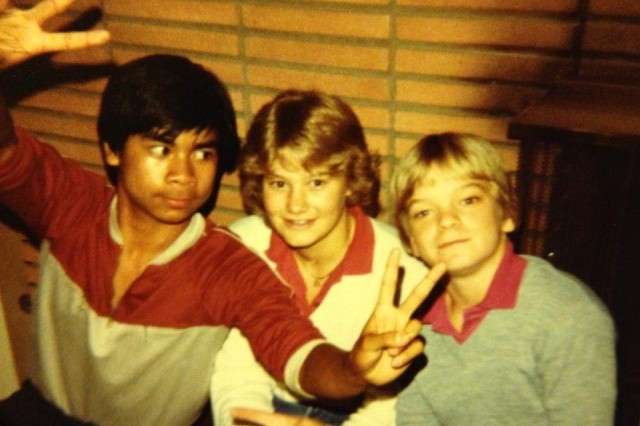 Three 1980s middle school boys posing for a photo together, one boy is giving the peace signs with both hands.